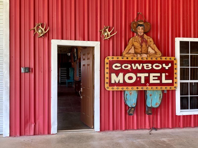 Cowboy Motel sign on a red barn next to front door